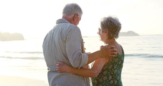 Senior couple embracing each other while standing on a beach during a beautiful sunset. Ideal for themes related to love, romance, retirement, senior lifestyle, leisure activities, and the beauty of nature. Can be used for marketing retirement communities, travel brochures, health and happiness lifestyle blogs, and greeting cards.