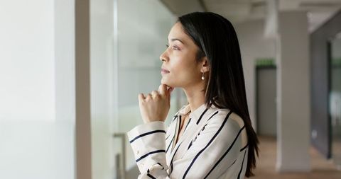 Businesswoman Deep in Thought Looking through Office Window