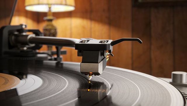 Turntable stylus tracking vinyl grooves under warm lamp glow midcentury living room