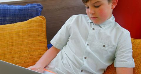 Young Boy Focused on Using Laptop at Home