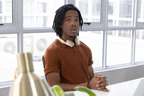 African american man in modern minimalist workspace wearing headphones and rust polo