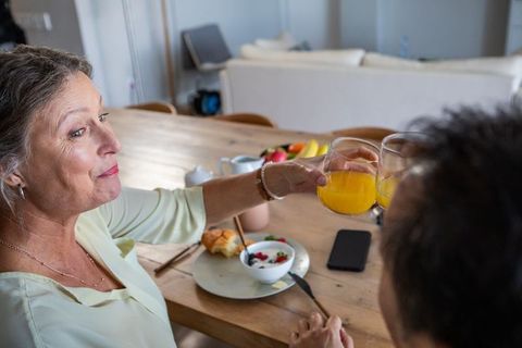 Senior woman and adult man enjoying breakfast together at home