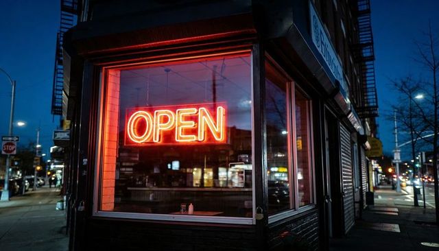 Glowing neon open sign illuminating corner diner window at dusk in urban night street
