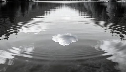 Monochrome lake ripples reflecting single cloud, minimalist tranquil water surface
