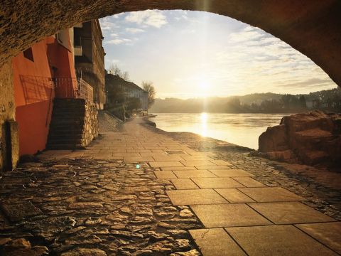 Sunlit Riverbank under Stone Archway at Dawn