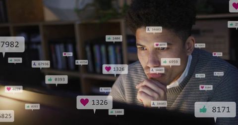 Focused young man analyzing social media engagement on laptop during late-night work