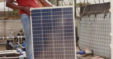 Technician installing solar panel by water storage in yard