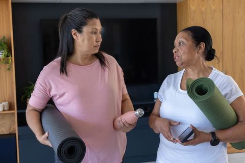 African american women holding yoga mats and chatting before home workout session