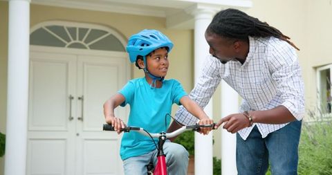 Father Teaching Son to Ride Bike in Front of Home