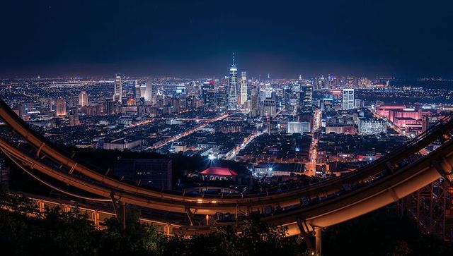 Illuminated city skyline at night with curving rail tracks