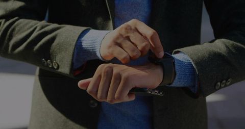 Man adjusting smartwatch in formal attire outdoors