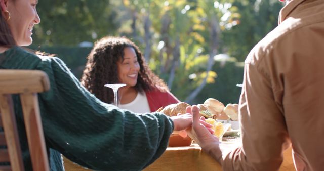 Happy diverse male and female friends saying prayer on thanksgiving celebration meal in sunny garden. Celebration, friendship, patriotism, american culture and tradition, unaltered.
