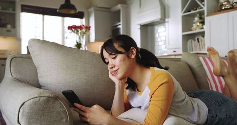 Relaxed Woman Browsing Smartphone in Cozy Modern Living Room with Neutral Decor