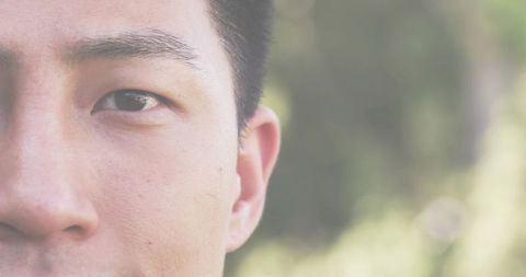 Contemplative Asian Man Half-Face Close-Up in Park with Soft Bokeh and Copy Space