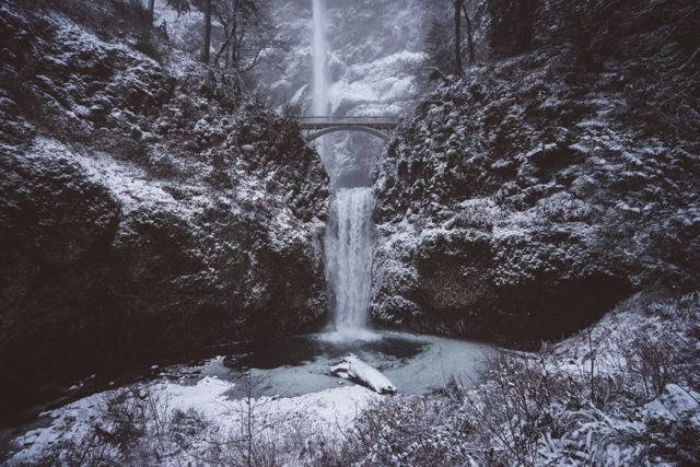 This enchanting scene of a snowy waterfall surrounded by a winter forest is perfect for use in travel-related publications, nature documentaries, or winter-themed marketing materials. The tranquil, cold atmosphere is ideal for conveying beauty and serenity during the winter months.