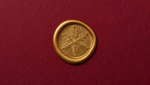 Gold wax seal with snowflake embossing on deep red paper for holiday luxury branding