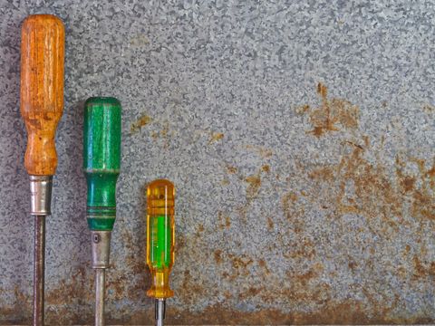 Three Rusting Screwdrivers on Weathered Surface