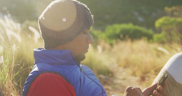 Young Person Relaxing Outdoors Using Smartphone in Sunlit Field - Download Free Stock Images Pikwizard.com