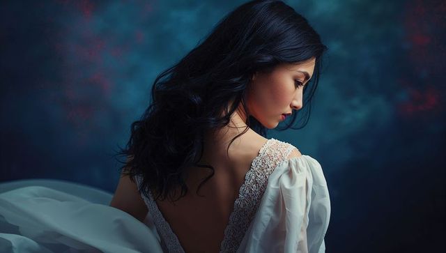 Elegant asian woman in white lace gown with curled hair, studio shot