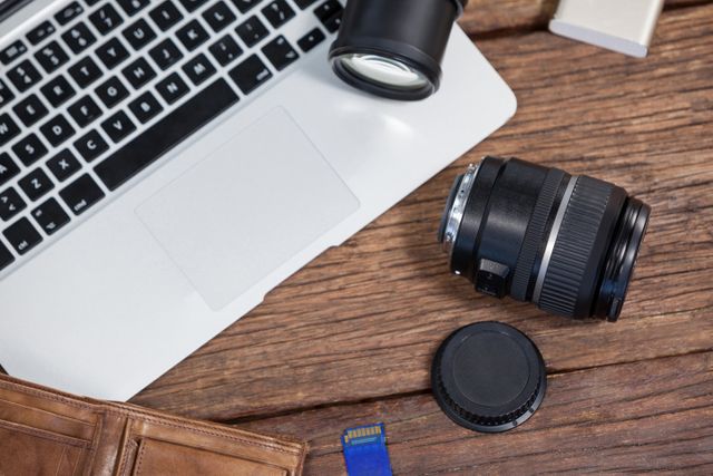 Close-up of digital camera, lens, memory card, laptop on table in studio