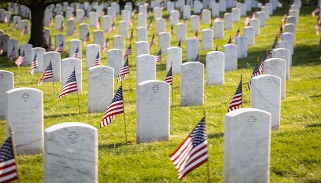 Uniform white headstones and american flags lining military cemetery grounds