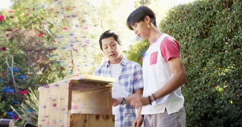 Adult and teen building birdhouse together in backyard woodworking and diy mentoring