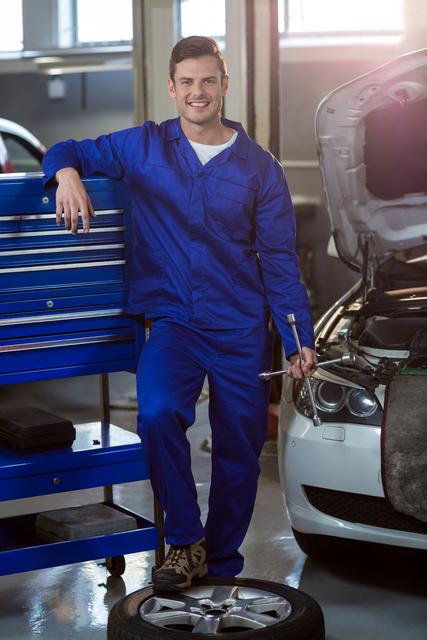 Portrait of mechanic with lug wrench in repair garage