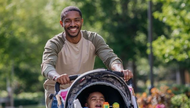Smiling caregiver pushing toddler stroller through sunlit park, joyful family moment