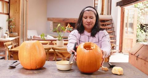 Senior Woman Carving Pumpkin for Halloween Decor on Autumn Day