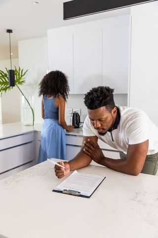 Couple reviewing mortgage paperwork on marble kitchen island planning modern home finance