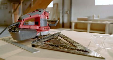 Cordless sander and measuring tools on carpentry workbench