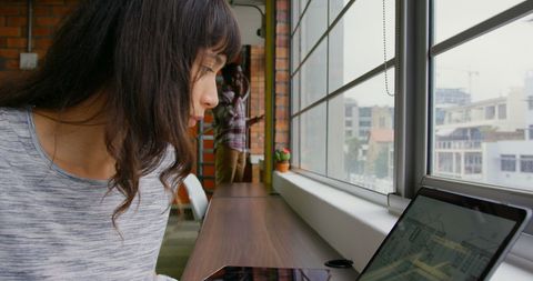 Caucasian Businesswoman Working on Laptop in Modern Office Near Window