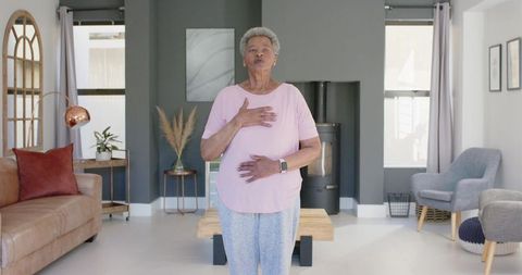 Senior african woman practicing deep breathing and mindfulness in cozy modern living room