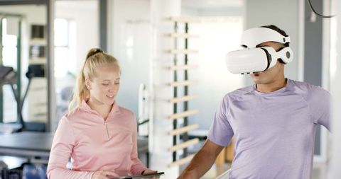 Man in Rehabilitation Using VR Headset Guided by Therapist with Tablet