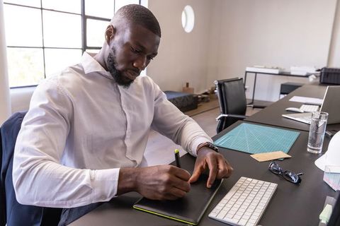African american architect sketching designs on tablet in modern office