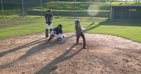 Baseball players in action on sunny field home plate