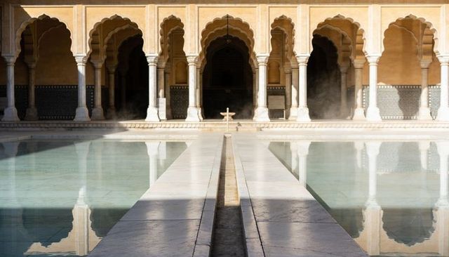 Symmetrical marble walkway reflecting pool in mughal-style courtyard with scalloped arches