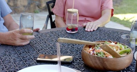 Friends Socializing Over Salad and Drinks in Backyard