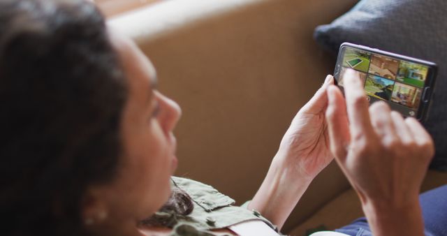 Woman holding smartphone browsing through online shopping sites, relaxing on couch. Useful for promoting e-commerce, technology services, online stores, or lifestyle content showcasing casual living, relaxation, and modern technology.