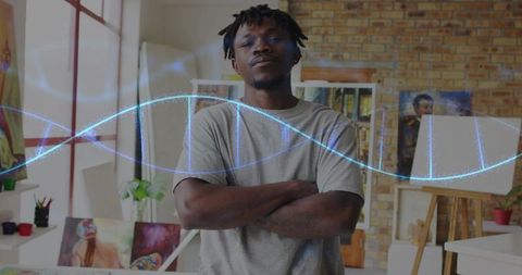 Standing artist crossing arms in bright studio with glowing dna helix projection