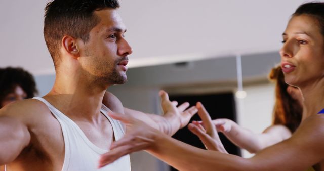 Ballet instructor guiding male dancer during practice session in modern studio. Suitable for use in articles about dance education, professional training, teamwork, and skill development. Can illustrate scenarios of mentorship, physical training discipline, and dance classes.