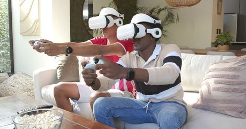Friends enjoying vr gaming at home with snacks and game controllers