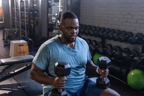 Focused man performing seated dumbbell press on bench in gym strength training session