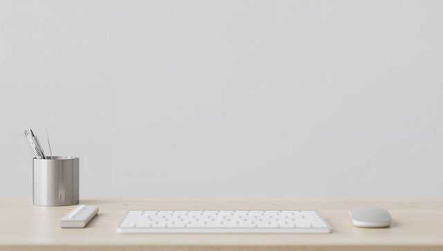 Minimalist workstation featuring white wireless keyboard, mouse, slim device and metal pen cup
