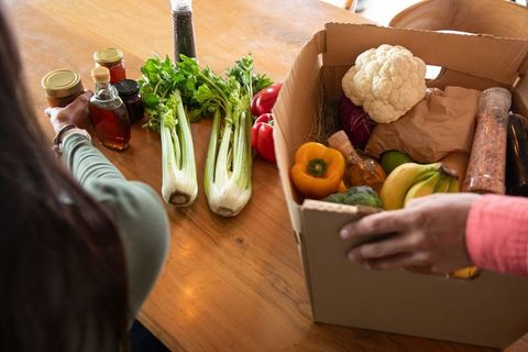 Couple Unpacking Fresh Organic Produce in Kitchen Setting