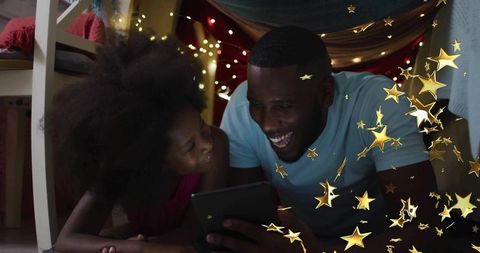 Father and Daughter Reading in Bed Fort with Magical Lights
