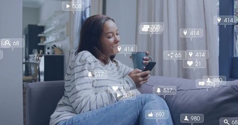 Relaxing on sofa scrolling smartphone with social notifications and blue mug