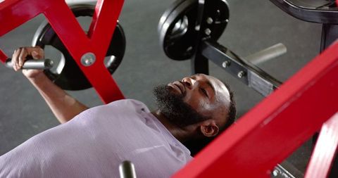 African american man lifting weights with bench press at gym