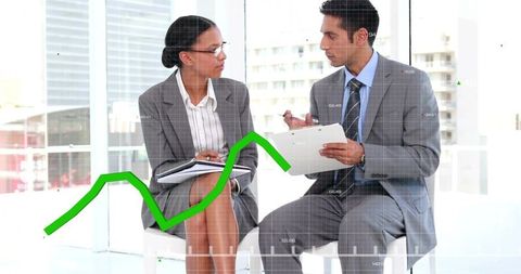 Professionals discussing rising green chart while reviewing data on clipboard in modern office