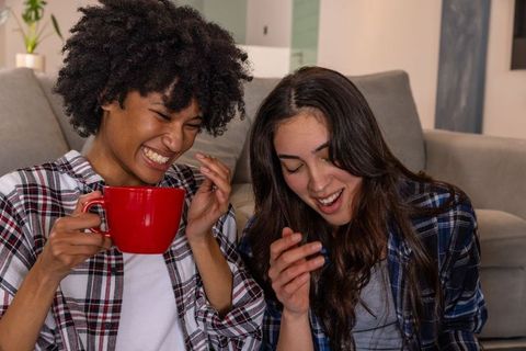 Diverse Female Friends Laughing with Red Mug Indoors